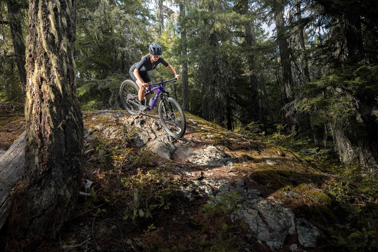 Woman riding the purple Liv Pique Advanced SL SE on a rocky trail