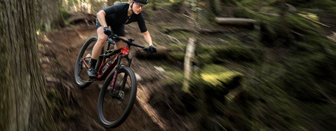 Woman riding a Liv Pique mountain bike through a forest